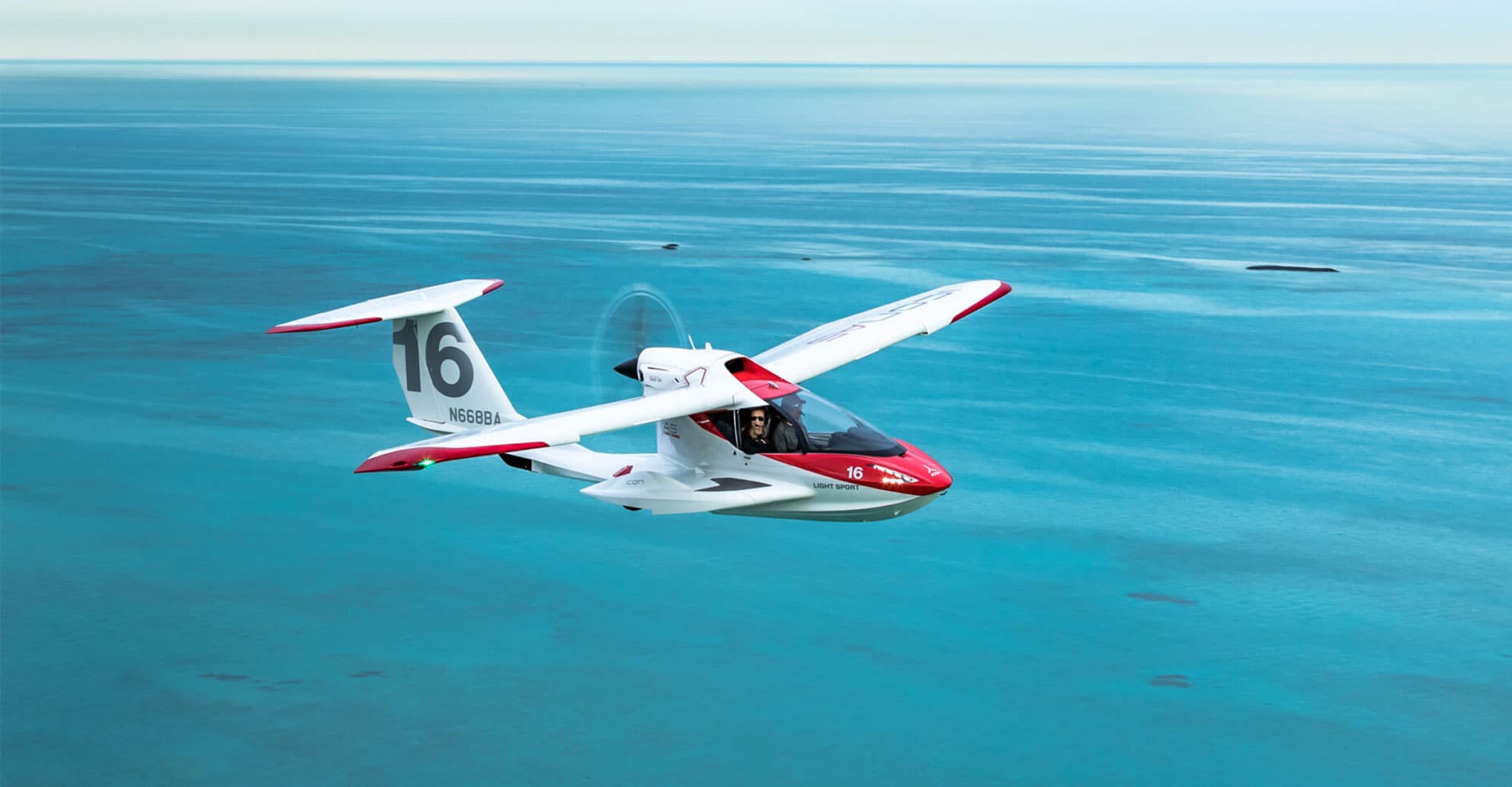 Amphibious light aircraft low over turquoise island water